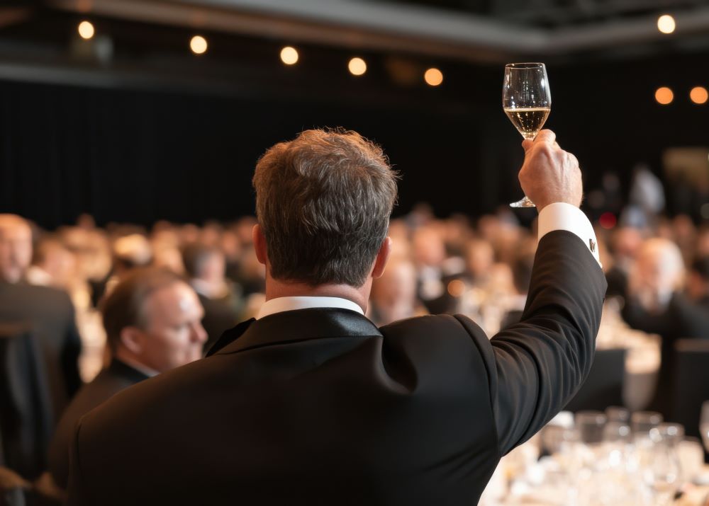 Person raising a glass of champagne at a charity gala 